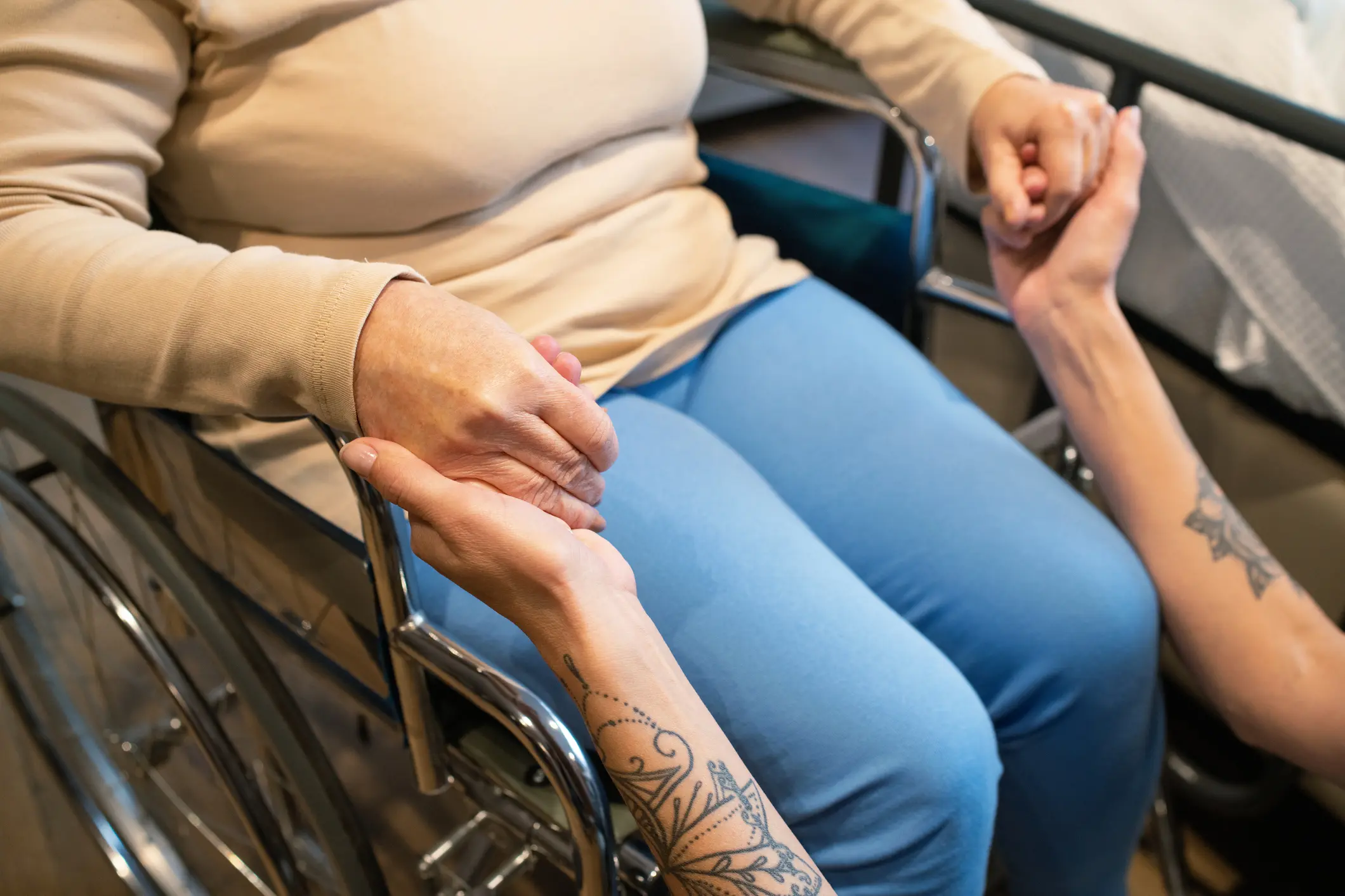 Person holding hands with someone in wheelchair.