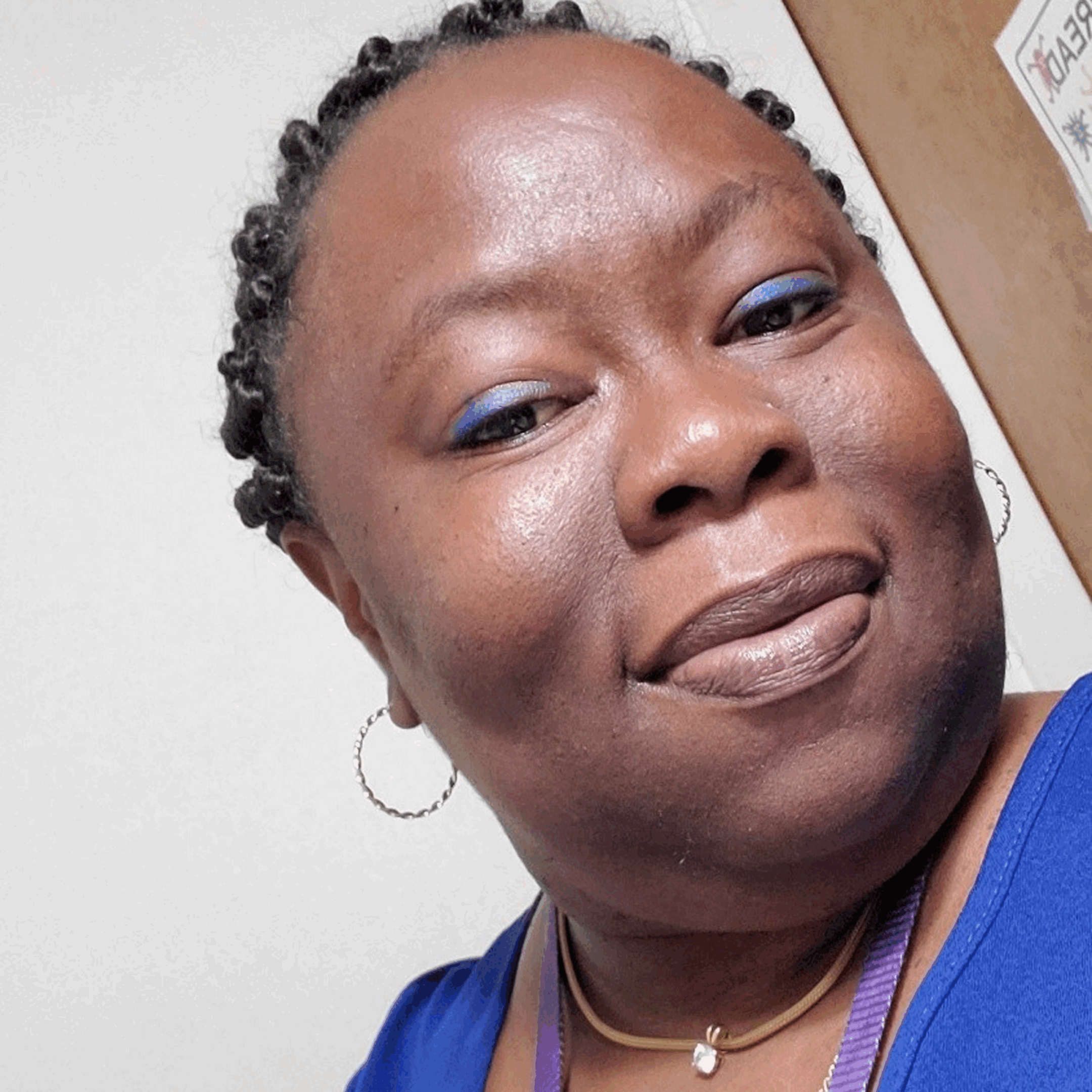 Smiling person with braided hair and earrings.