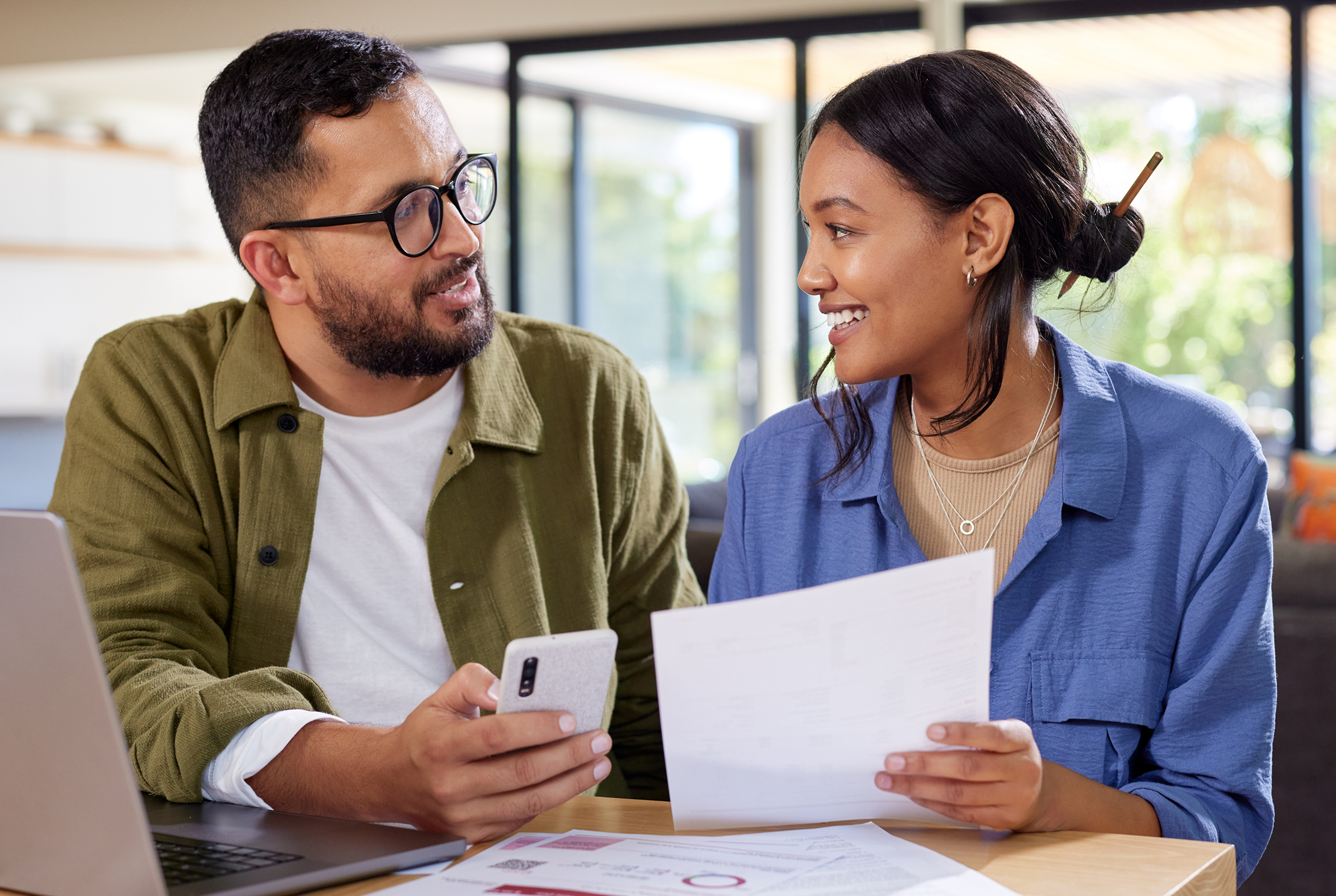 Couple discussing paperwork at home table.